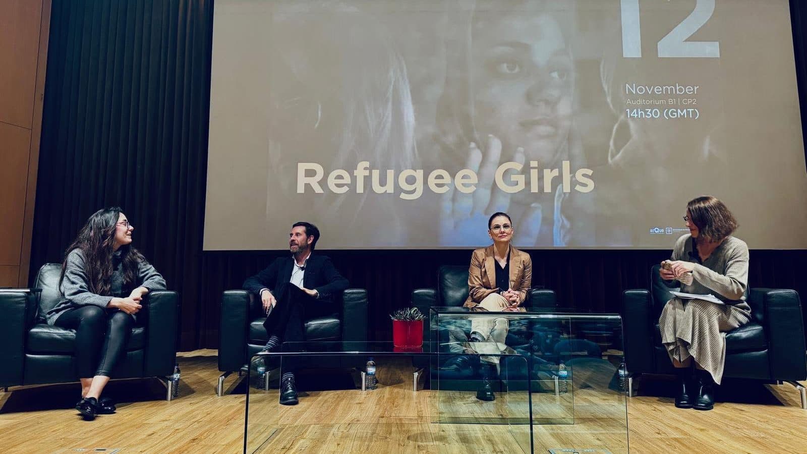 Elisa Gamba during the Refugee Girls panel, seated with the other speakers in front of the event screen